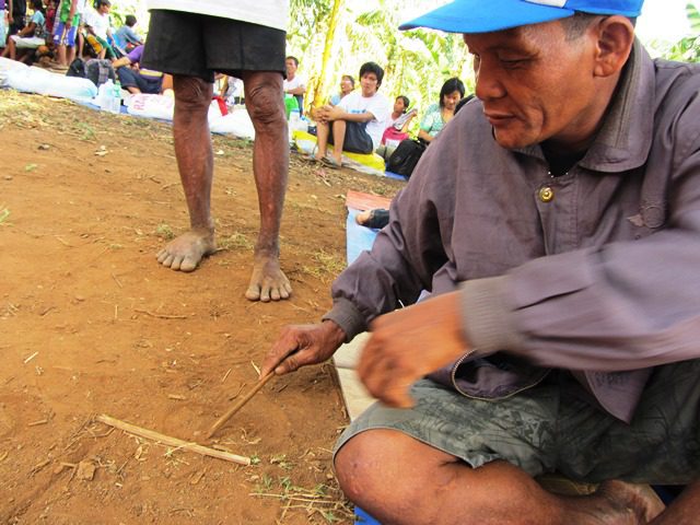 Mangyan leader Altang Dawseg sketches on the ground how a dam being constructed in their village would submerge farms and isolate the upland Mangyan. (Apr 2013 Photo by M. Salamat / www.bulatlat.com)