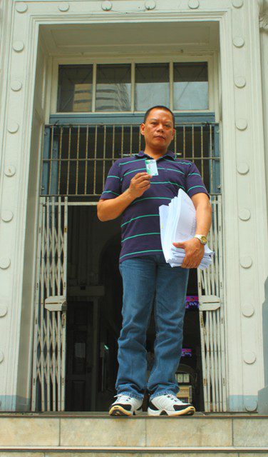 Rolly Mira Panesa steps out of the Department of Justice main building, showing his company ID and a copy of the complaint he filed against his torturers. (Photo by Ronalyn V. Olea/Bulatlat.com)