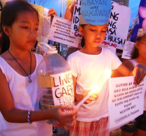 Women's group Gabriela light candles along Araneta, Quezon City (Photo by Anne Marxze D. Umil/Bulatlat.com)