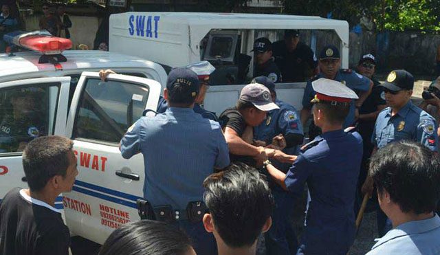 Policemen grab a consumer activist during a protest action in front of the Albay Electric Cooperative in Legazpi City, February 24. (Photo by Rico de Mesa Manallo / bicoltoday.com )