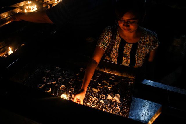 A member of Talents Association of GMA (TAG) lights a candle at the Sacred Heart Parish, June 3. (Photo by Manila Today)