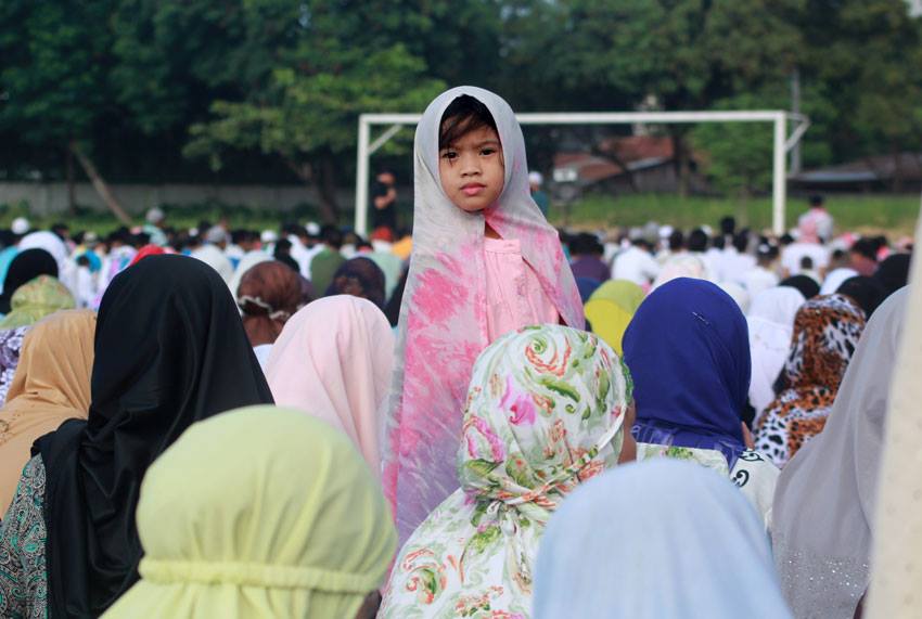 A Muslim child watches around the field, while elder Muslims listen to the preaching of their Imam during the celebration of the Eid’l Fitr on Friday at Tionko Football Field in Davao City.
