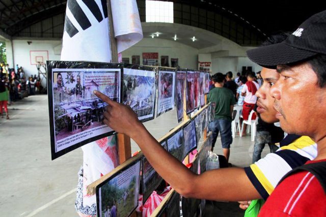 People who visited the wake of Alcadev director Emerito Samarca look at the photos of the “Lianga Massacre” displayed in the Capitol Gym in Butuan City.