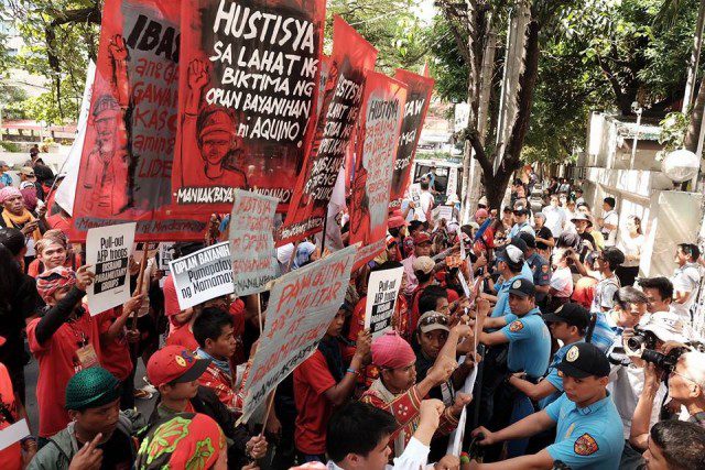 Protesters face anti-riot police men in front of the DOJ office in Manila (Photo by Manila Today)