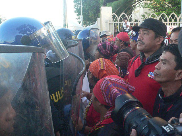 STAND-OFF. Bayan Muna Rep. Carlos Zarate, Lumad women leaders, and other Mindanao activists in a staredown with anti-riot police at Baclaran church gate. (Photo by D.Ayroso/Bulatlat.com)