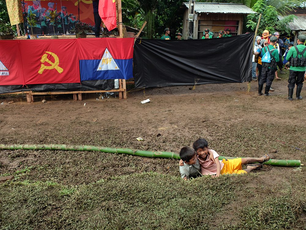 Two young boys slip on the muddy ground and laugh their heads off, obviously having fun and wanting the program to start already. (Kitcharao, Agusan del Norte)