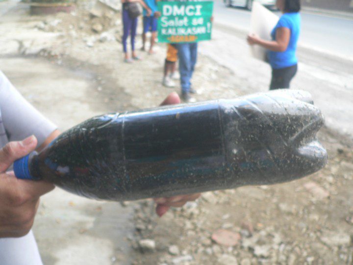 BLACK WATER. Protesters show a sample of sea water darkened by coal sediment taken from Calaca coast (Photo by D.Ayroso/Bulatlat)