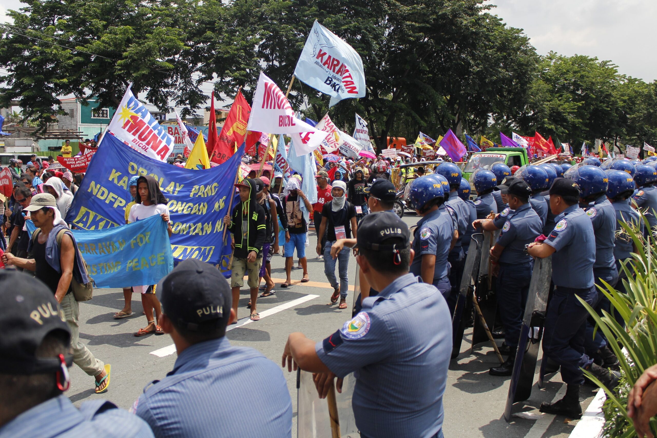 Policemen look on as rallyists march along Batasan Road. (Photo by Karen Ann Macalalad/Bulatlat)