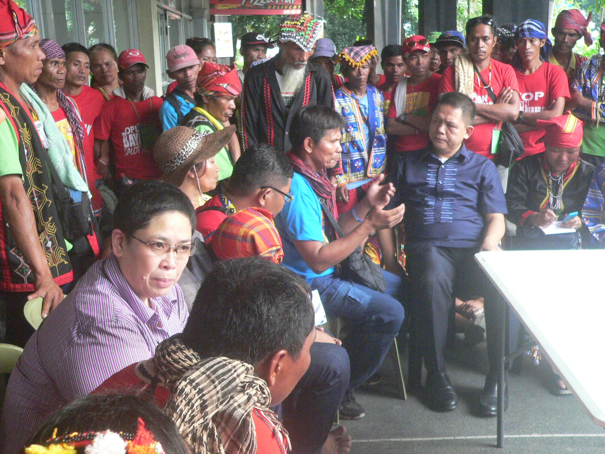 NCIP officer-in-charge Director Lee Arroyo (seated at left, wearing glasses) and lawyer Edwin Caliba, executive assistant to the NCIP chairperson (seated, second to right, in navy blue polo). The NCIP officials and Lumad leaders talked outside the building of the office (Photo by Dee Ayroso/Bulatlat)