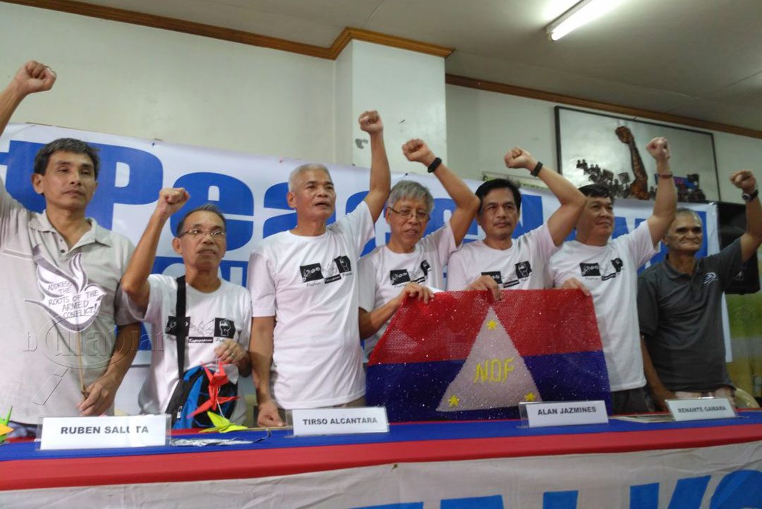 (L-R) NDFP consultants Kennedy Bangibang, Ruben Saluta, Tirso Alcantara, Alan Jazmines, Renante Gamara, Ernesto Lorenzo and Jaime Soledad raise their clenched fists as they are welcomed by supporters, Aug. 17. (Photo by Ronalyn V. Olea / Bulatlat)