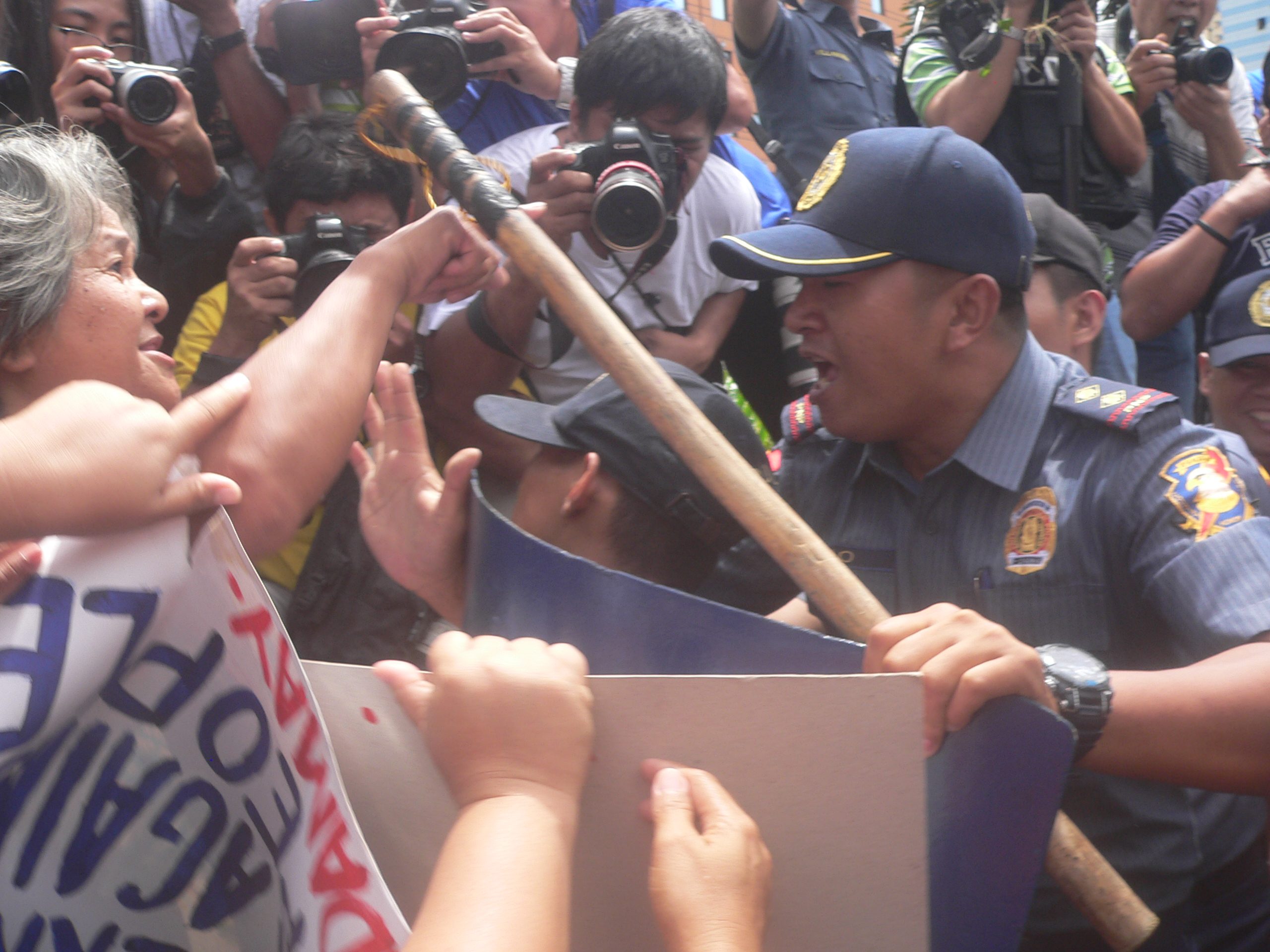 Sixty-year-old urban poor leader Estrelita Bagasbas in shouting match with a police who tried to hit her in the leg with a truncheon. (Photo by Dee Ayroso/Bulatlat)