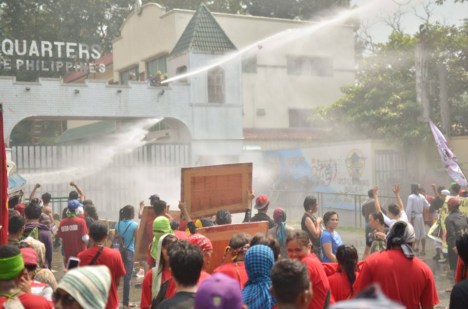 Drenched protesters stayed their ground amid the water cannon blasts by AFP personnel at the gate of Camp Aguinaldo. (Photo by Carlo Manalansan/Bulatlat)