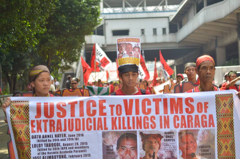 Sandugo delegates carry a streamer with images of slain activists in Caraga region (Photo by Carlo Manalansan/Bulatlat)