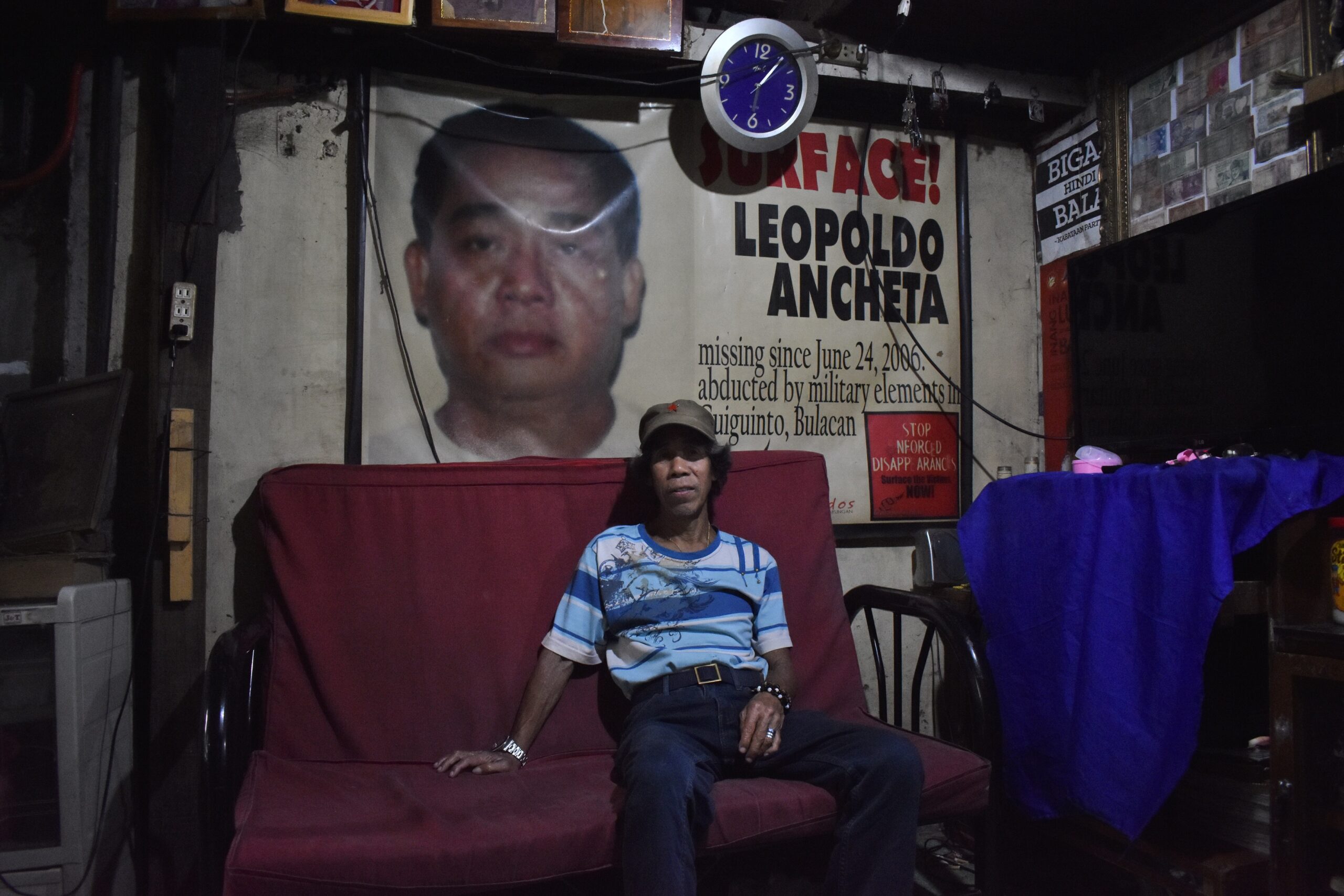 Romeo Ancheta at his living room, with a tarpaulin of his missing brother Leopoldo. (Photo by Ian Irving Bazarte/Bulatlat)